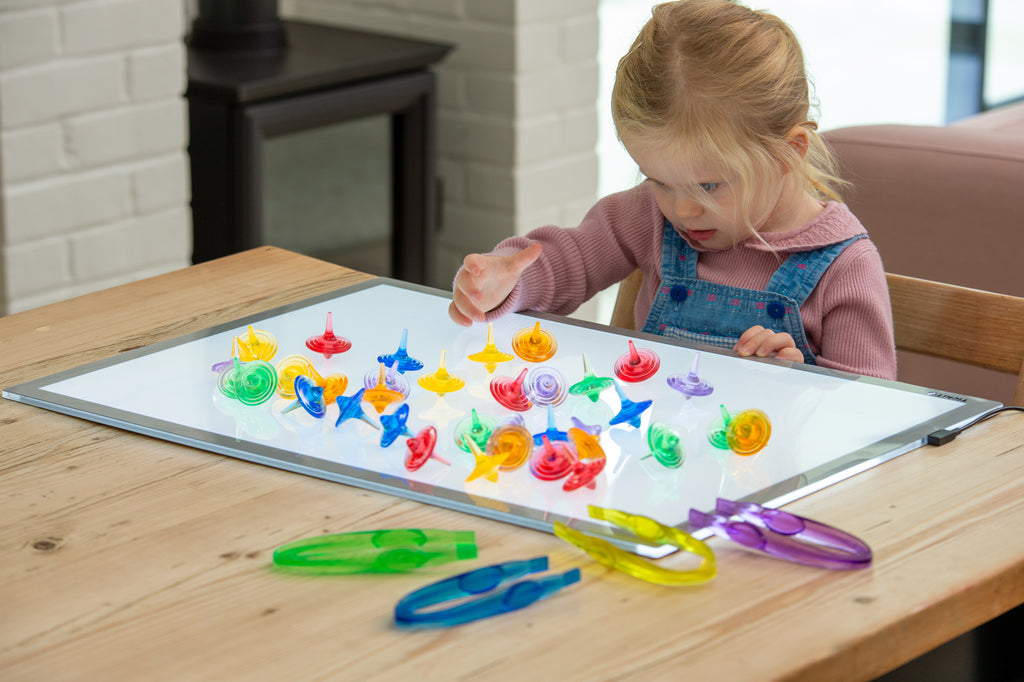 Translucent color spinners scattered on a tabletop as a child plays