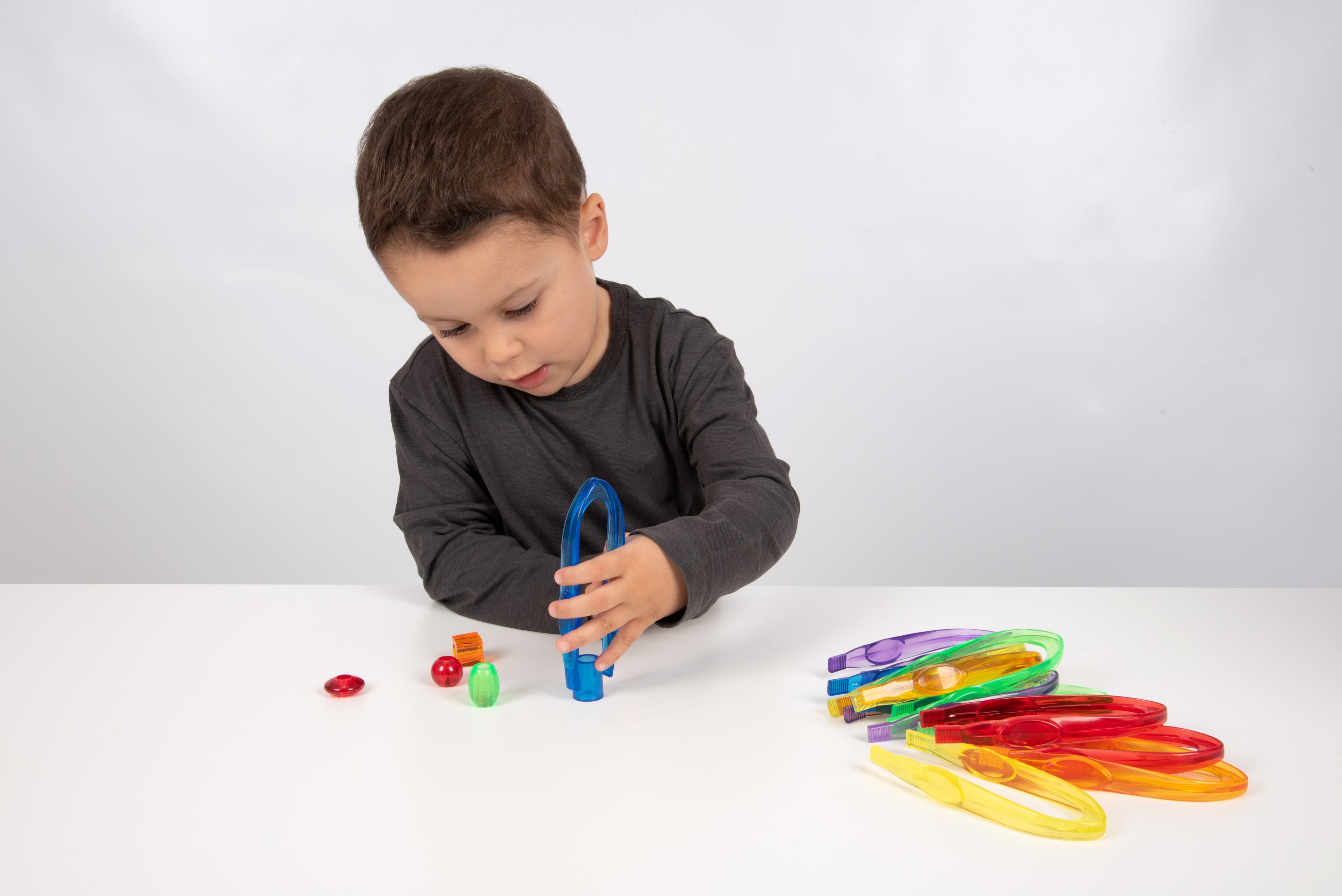 Translucent color tweezers set with multicolor pieces laid out on a table.