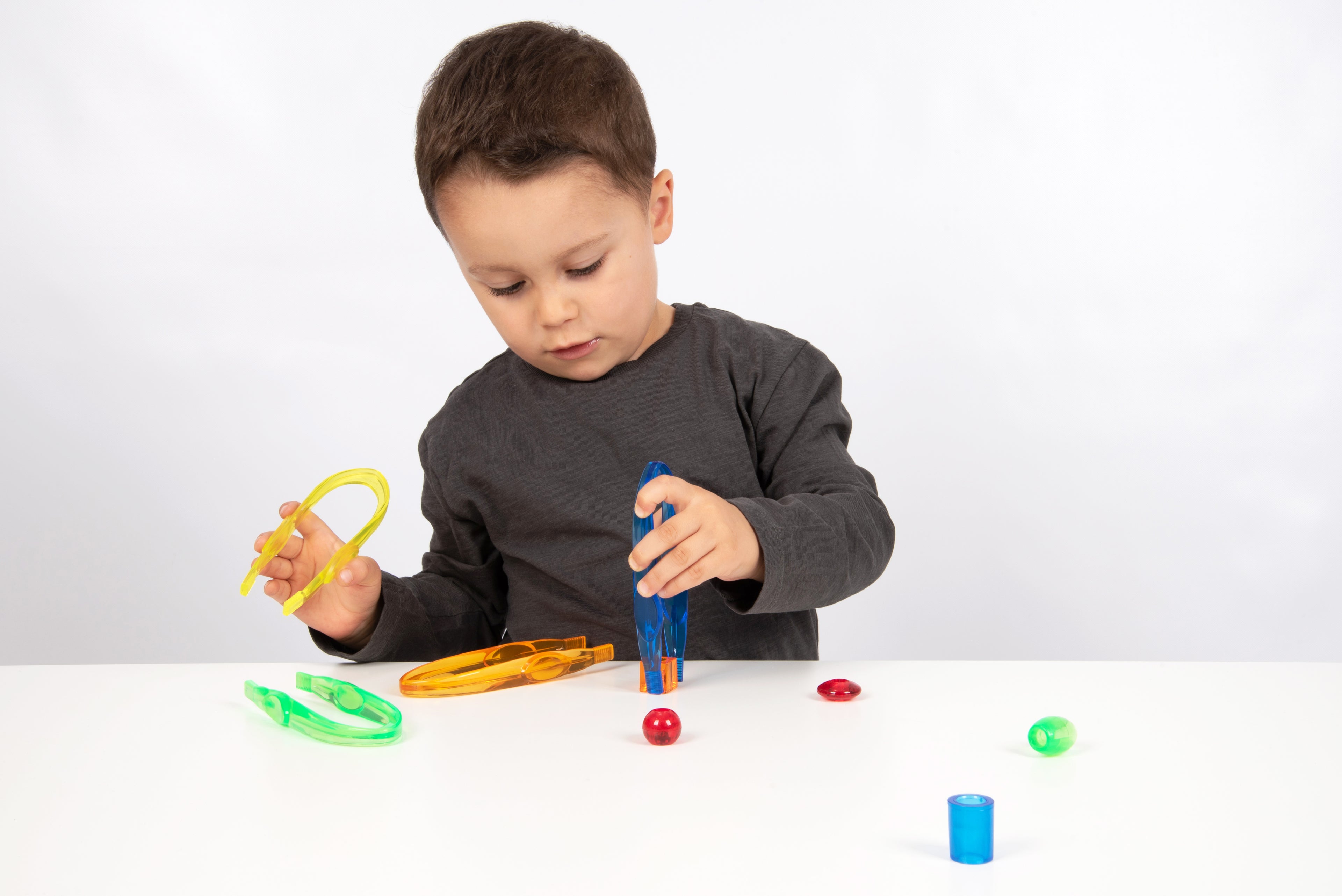 Translucent color tweezers in bright colors, held by a child while playing.