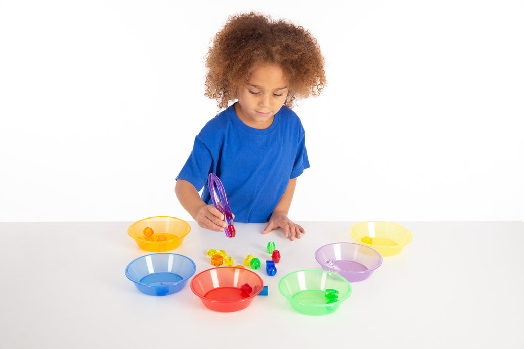 Translucent color tweezers set in bright colors, held during play with bowls.
