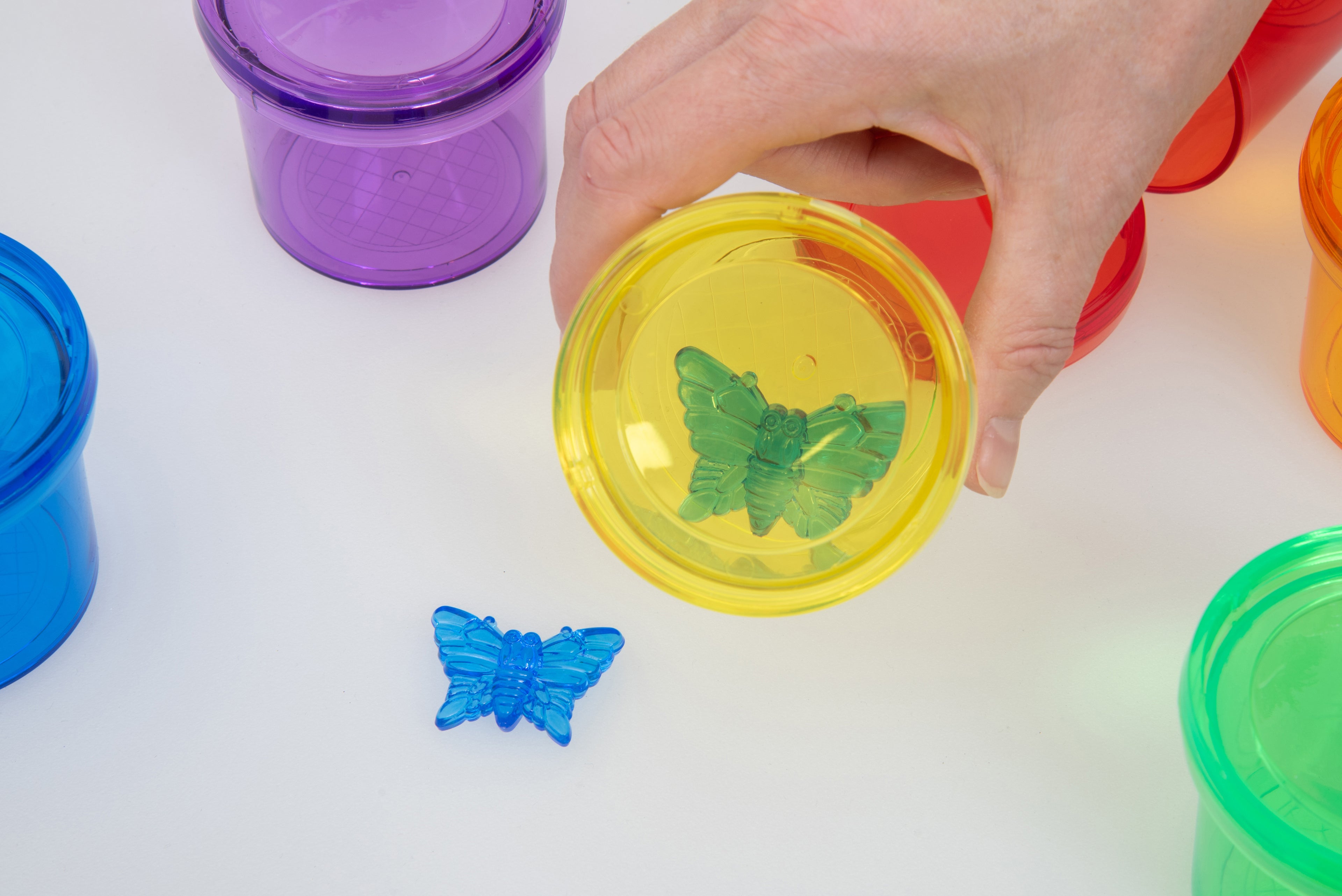 Hand holding a yellow translucent color viewer cup with butterfly slide