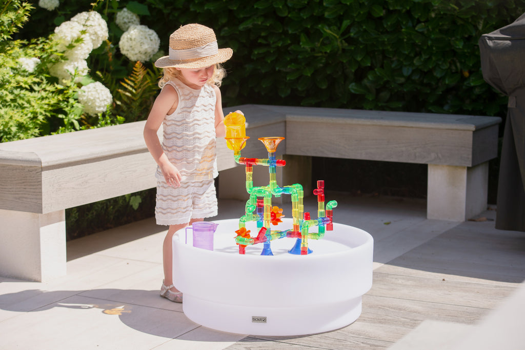 Translucent water pipe toy on a white outdoor basin with colorful tubes and orange funnels