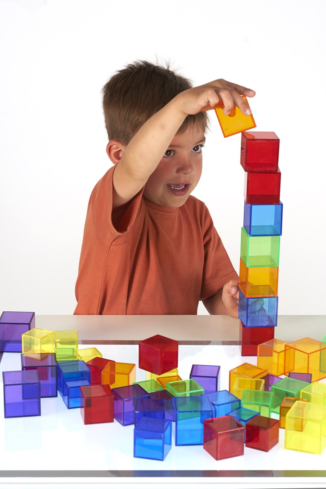 Translucent building cubes set, child stacking colorful cubes on a table