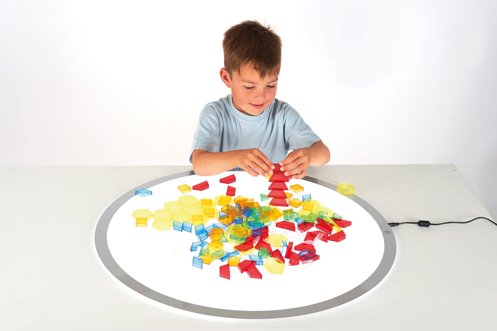 Translucent hollow blocks in mixed colors, child building on a round play mat