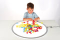 Translucent hollow blocks in mixed colors, child building on a round play mat