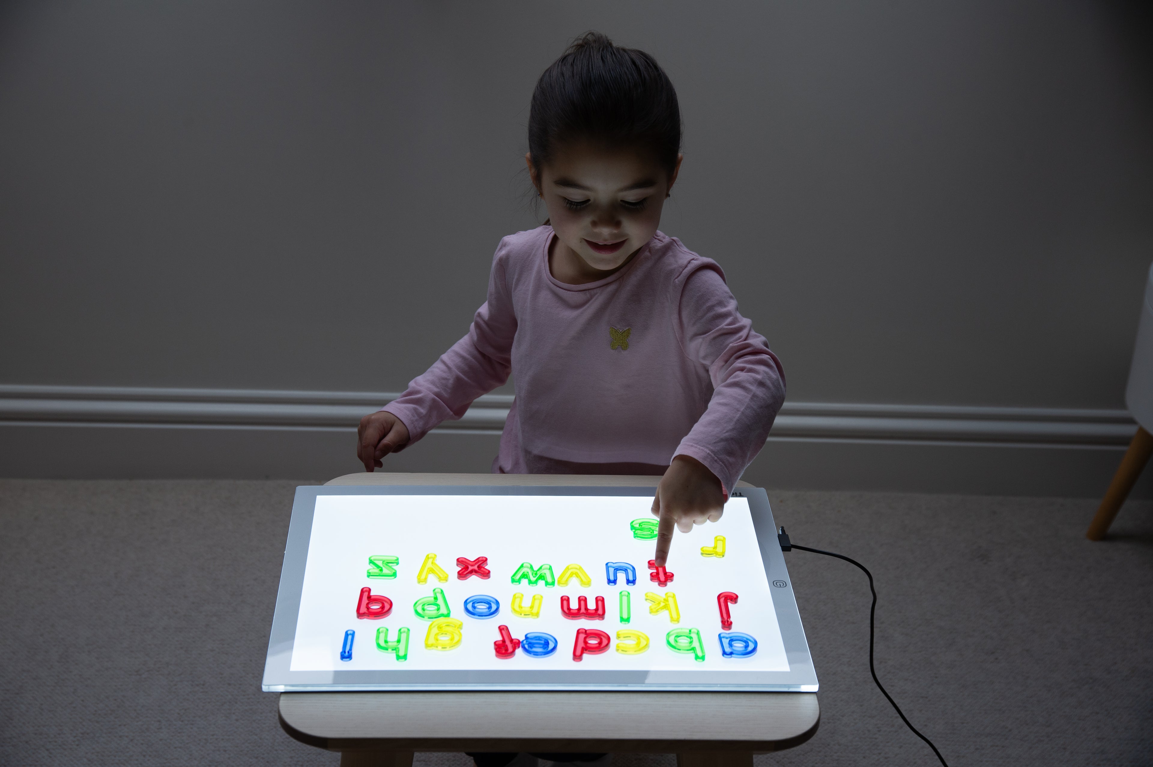 Translucent lowercase letters on tablet screen with child hands
