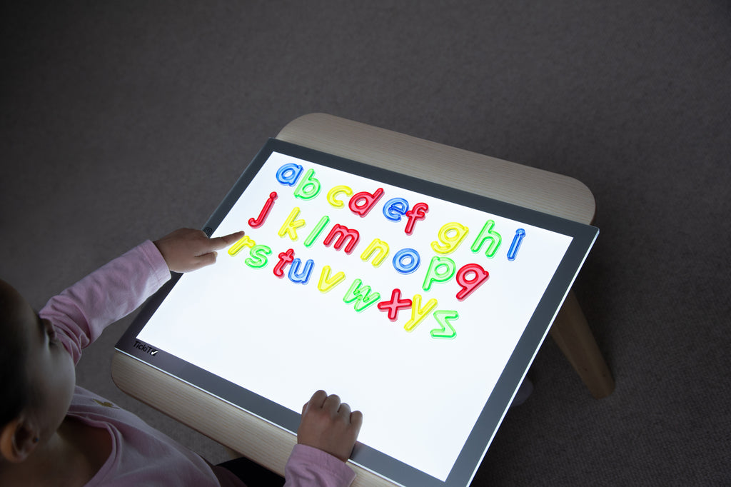 Translucent lowercase letters displayed on tablet screen with hands