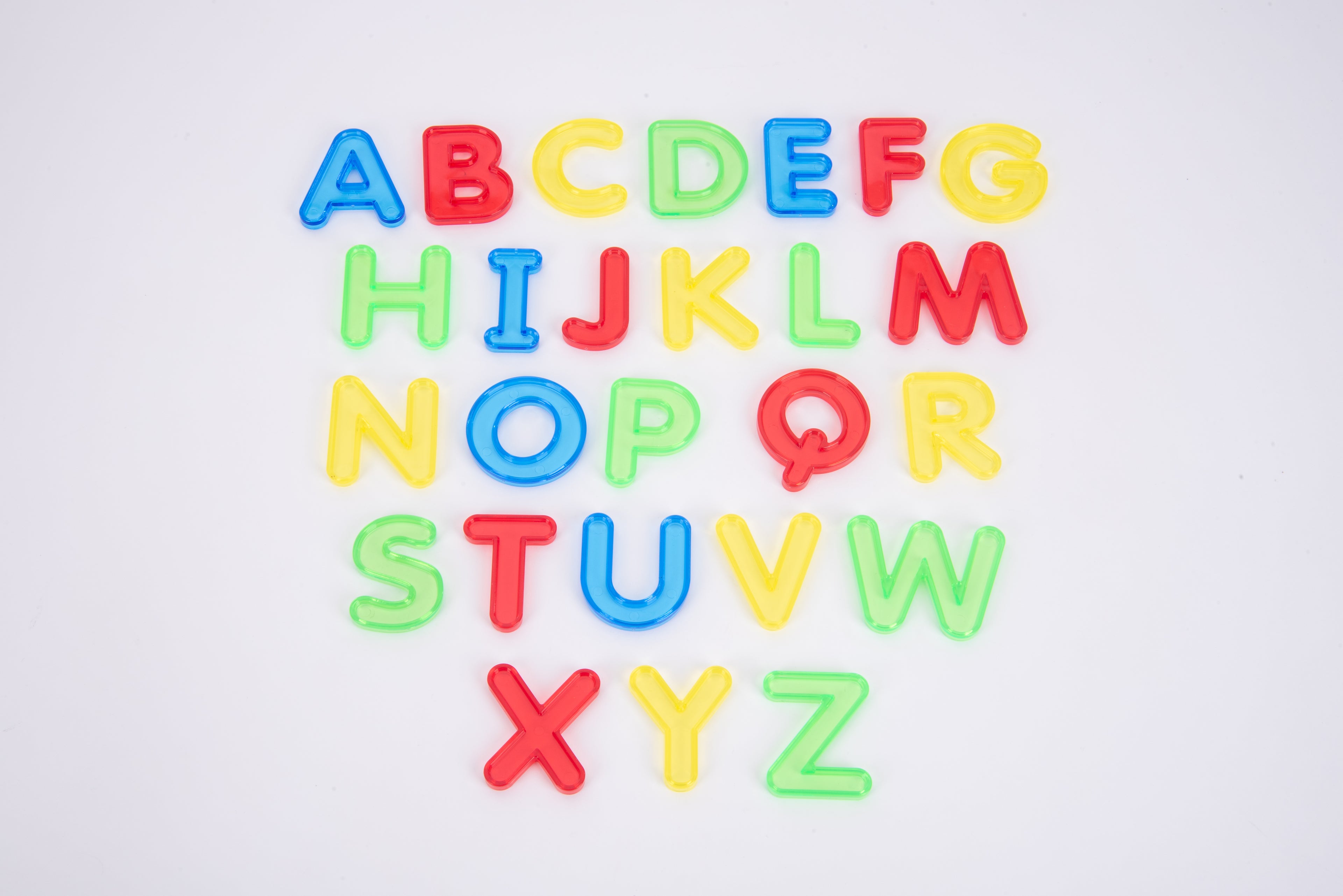 Colorful translucent uppercase alphabet letters A–Z on white surface, spaced layout