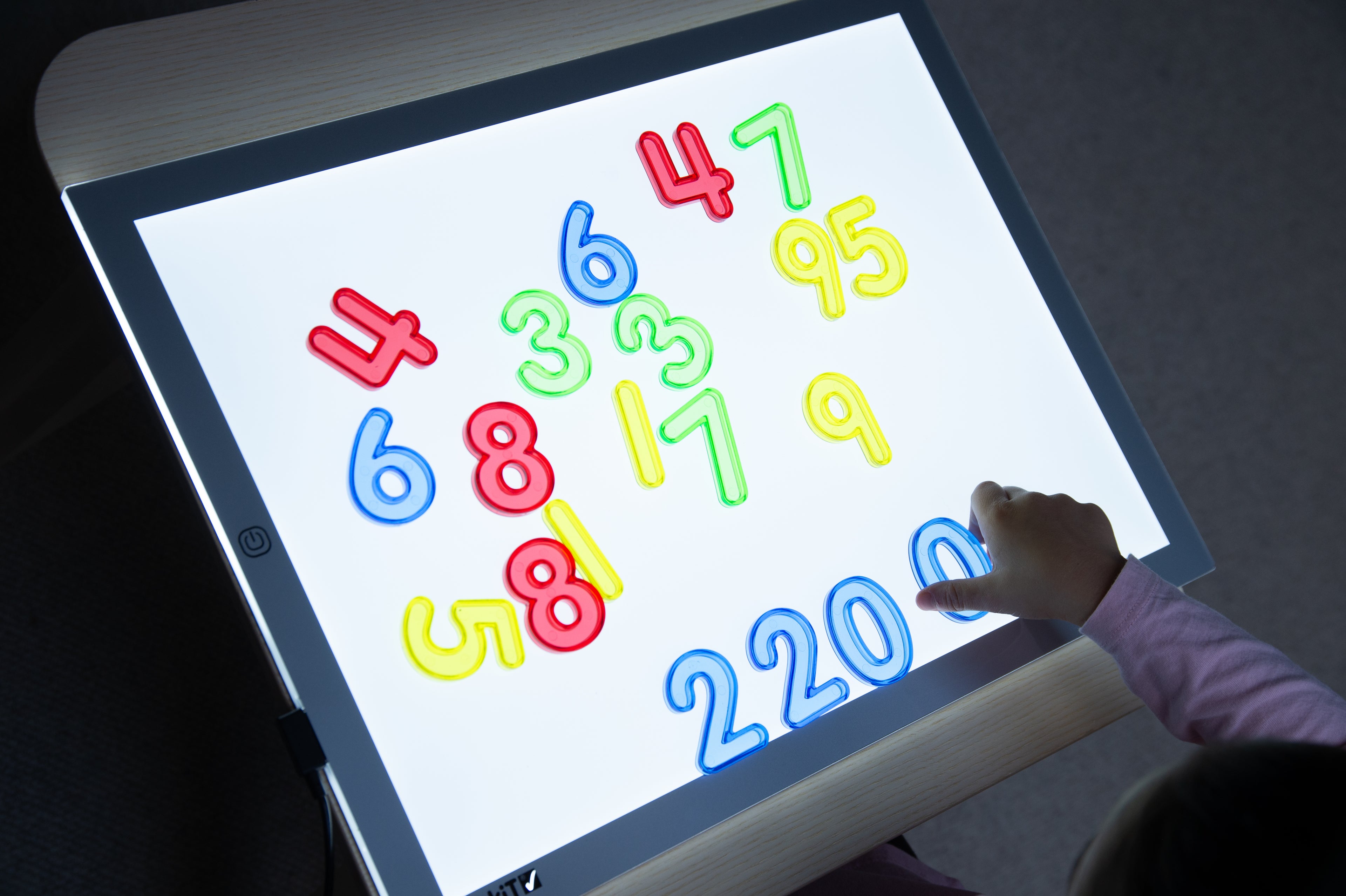 Backlit tablet displaying colorful translucent numbers and digits (1–20, 4–9).