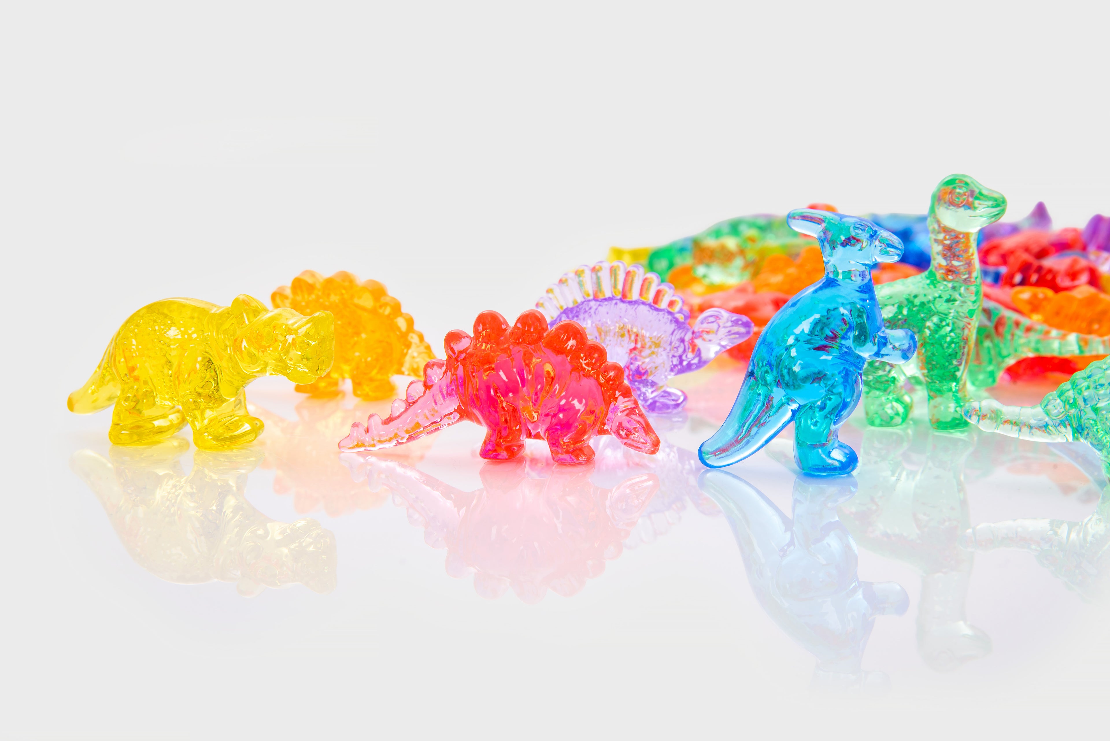 Translucent dinosaur figurines in bright colors, close-up view.