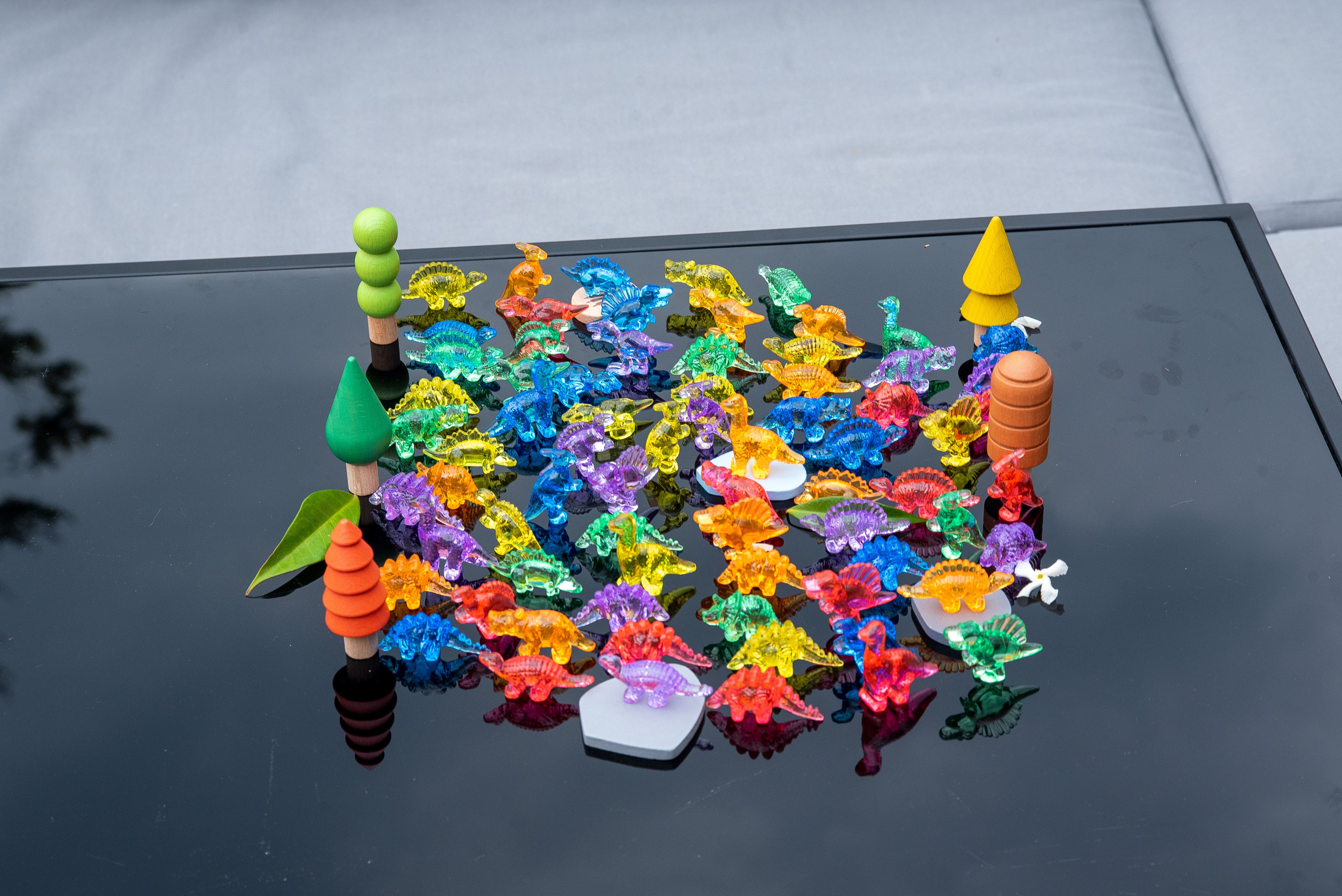 Translucent multicolor dinosaur figurines with small accessories, spread on a table.