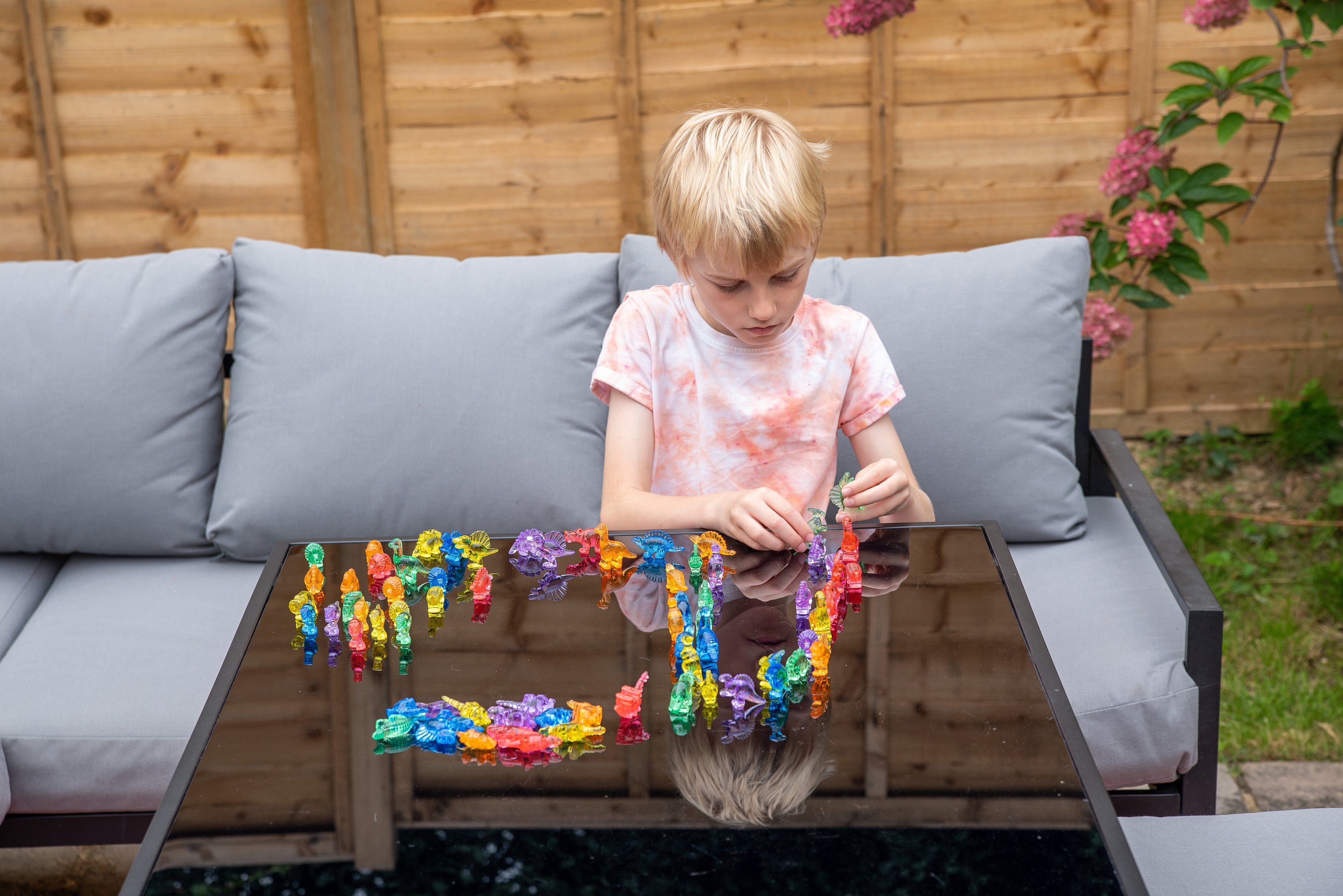 Child holding translucent multicolor dinosaur figurines while playing.