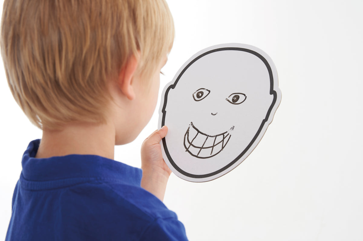 Child pointing at a black-and-white emotion face card with gritted teeth