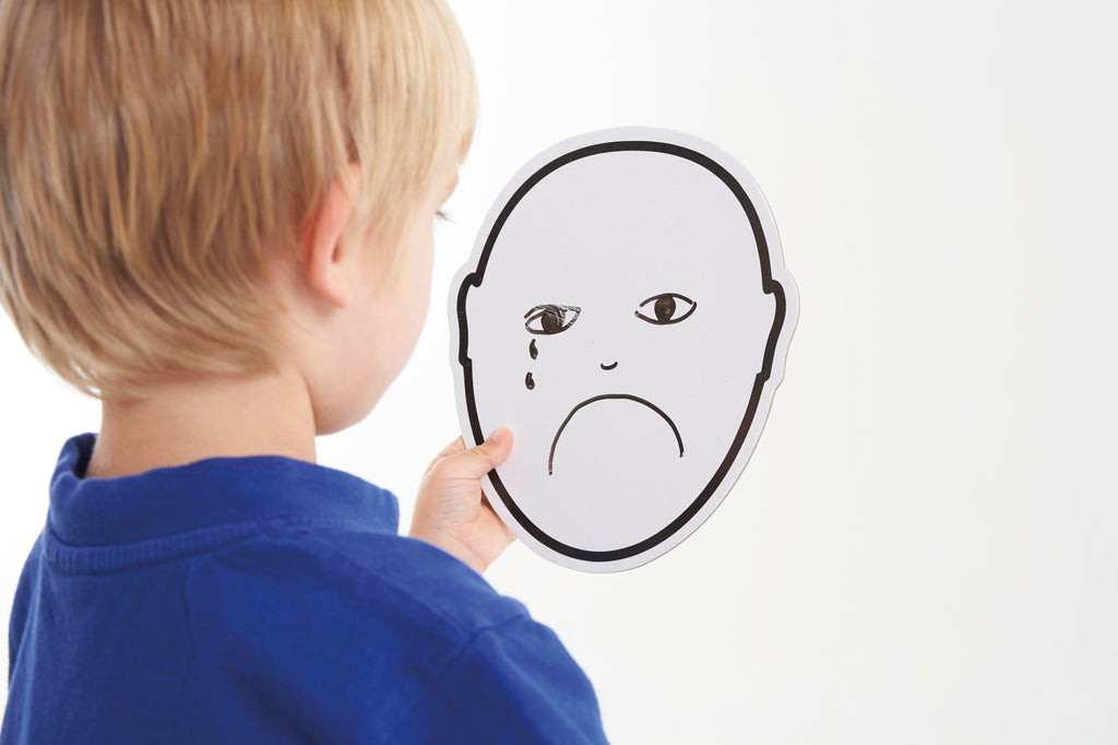 Child holding a black-and-white emotion face card with a worried frown