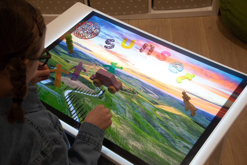 Play mat on table showing landscape with rainbow sky, colorful letters, and winding path