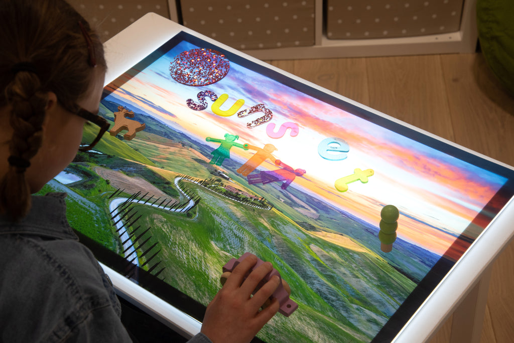 Kids play mat used on a table, with rainbow sky, green fields, and winding fence