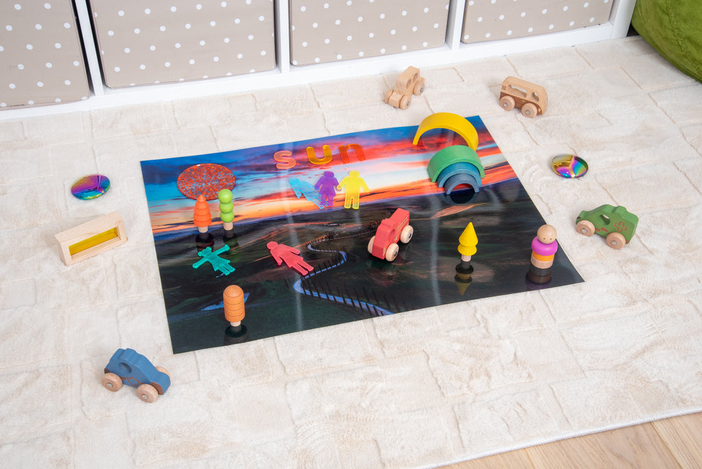 Play mat with winding road scene, rainbow arch, and colorful wooden toy pieces