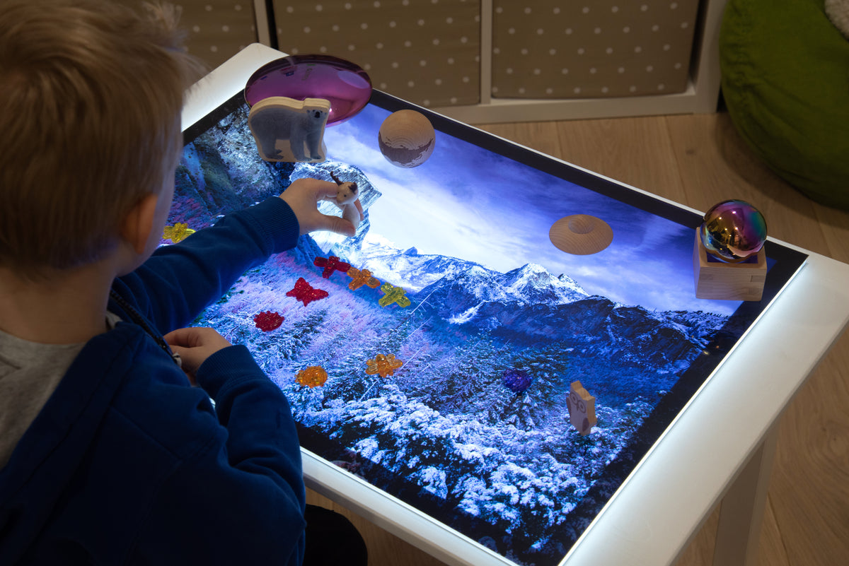 Child hands near planet toys on snowy mountain play mat