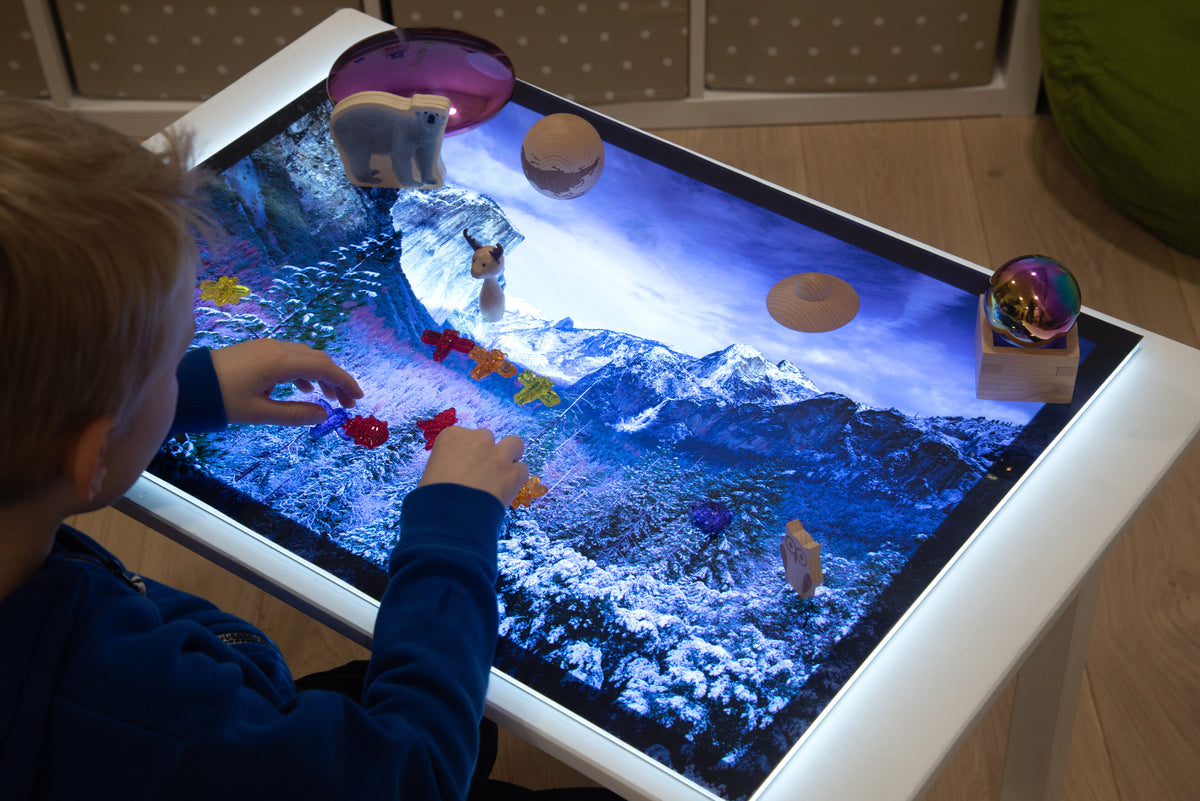 Child playing on winter play mat with planets, rocks, and snowy mountain artwork