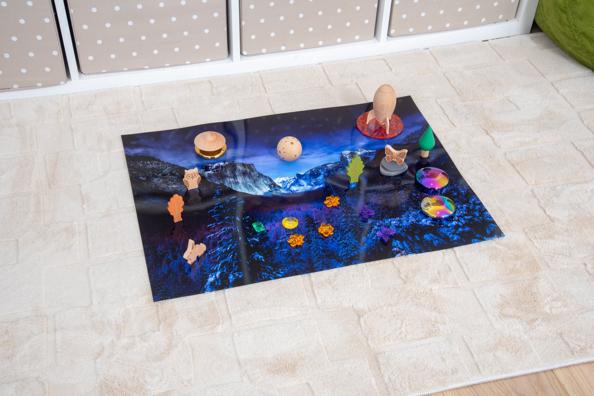 Winter play mat on floor with planet-themed toys and snowy mountain scene