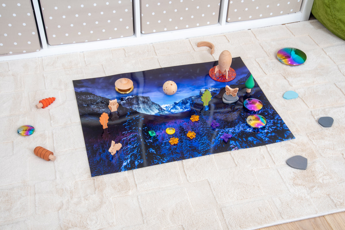 Snowy mountain play mat with planet-themed accessories scattered around