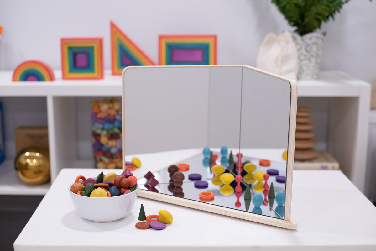 Wood-framed 4-way mirror reflecting colorful peg pieces and parts