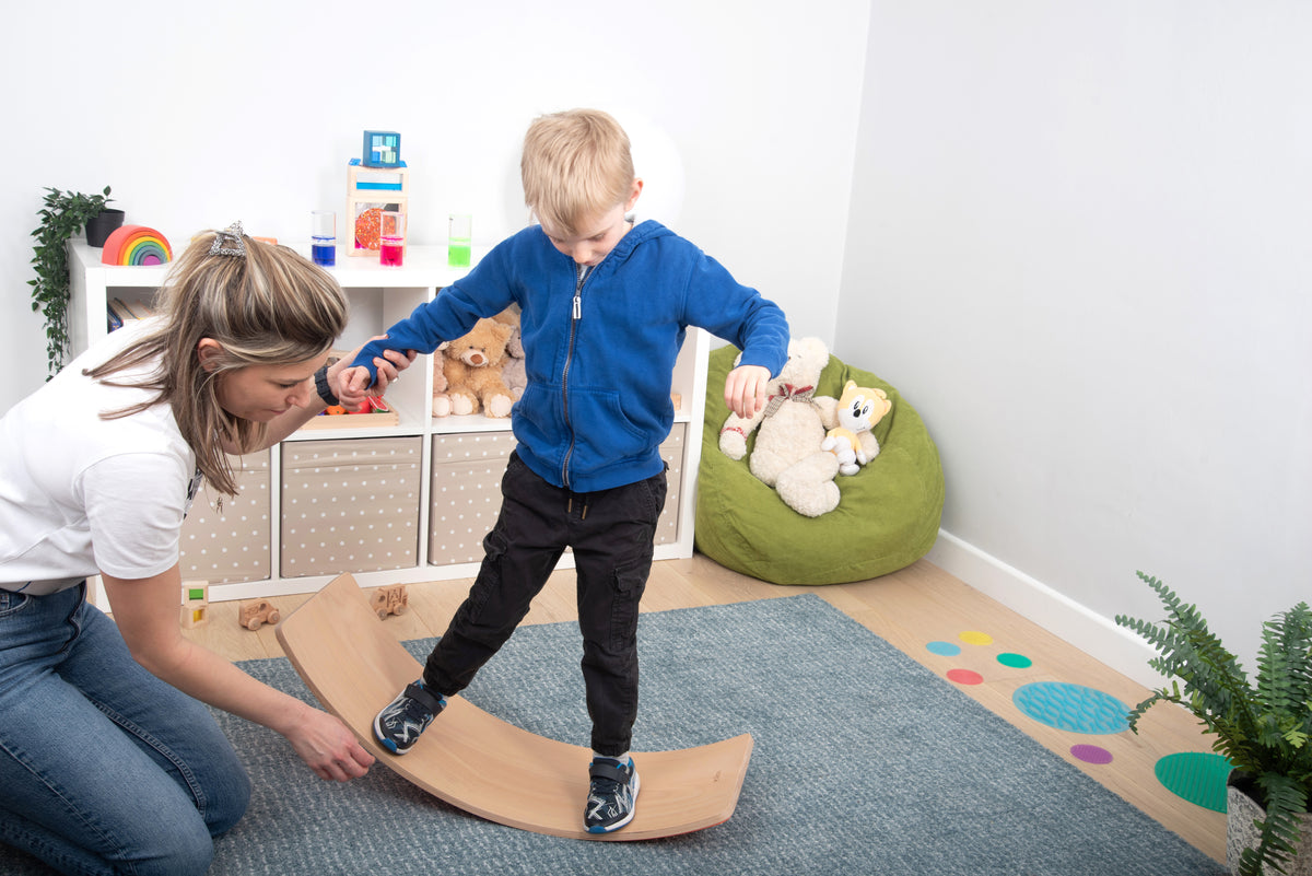 Curved light-wood balance board in crescent shape, child using the arched surface