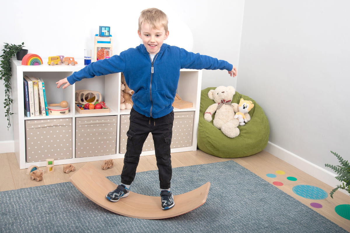 Crescent wooden balance board with light wood finish, child standing on it
