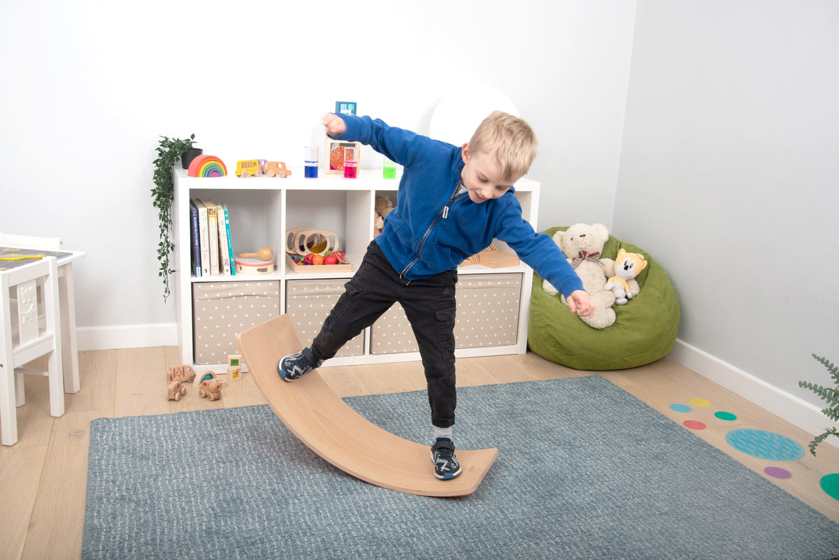 Light-wood crescent balance board with smooth arched design, child standing upright