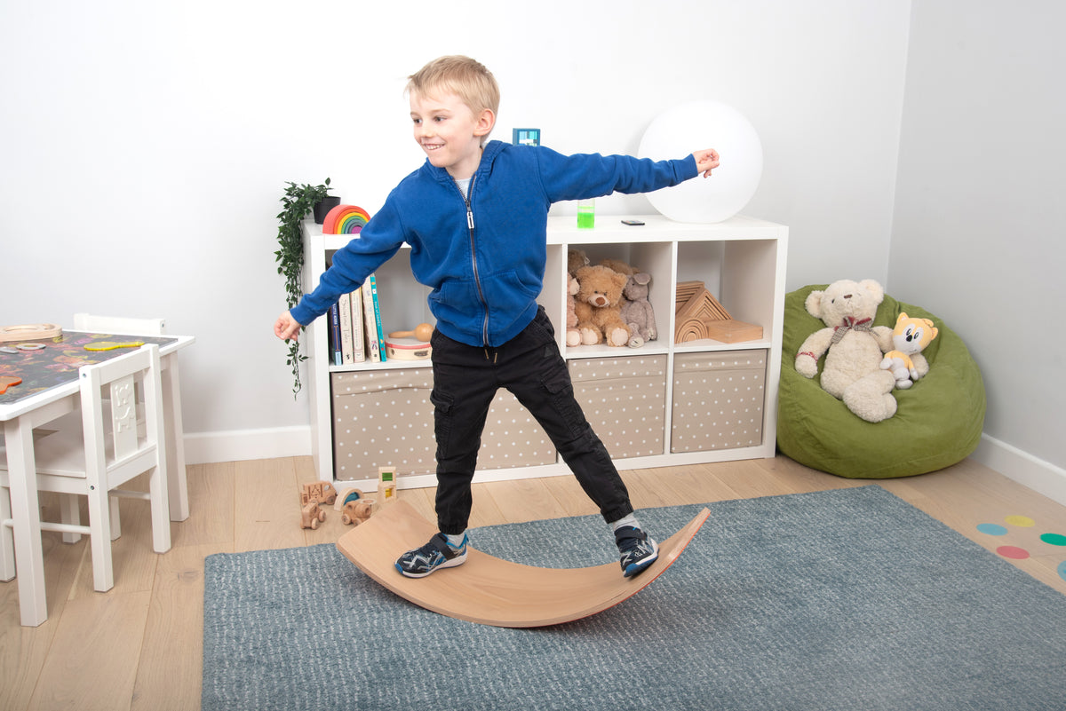 Curved wooden balance board with light wood finish, child stepping on the arch