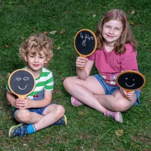 Wooden-framed black chalkboards with chalk drawings, held by two children