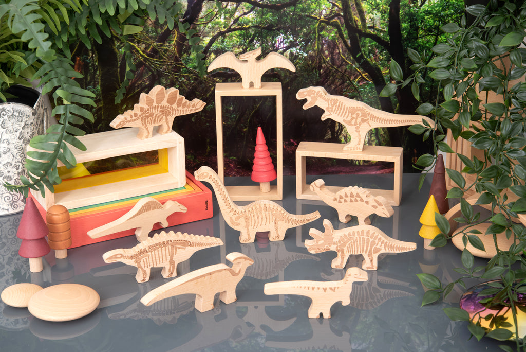 Assorted wooden dinosaur blocks arranged for play, light wood with engraved details