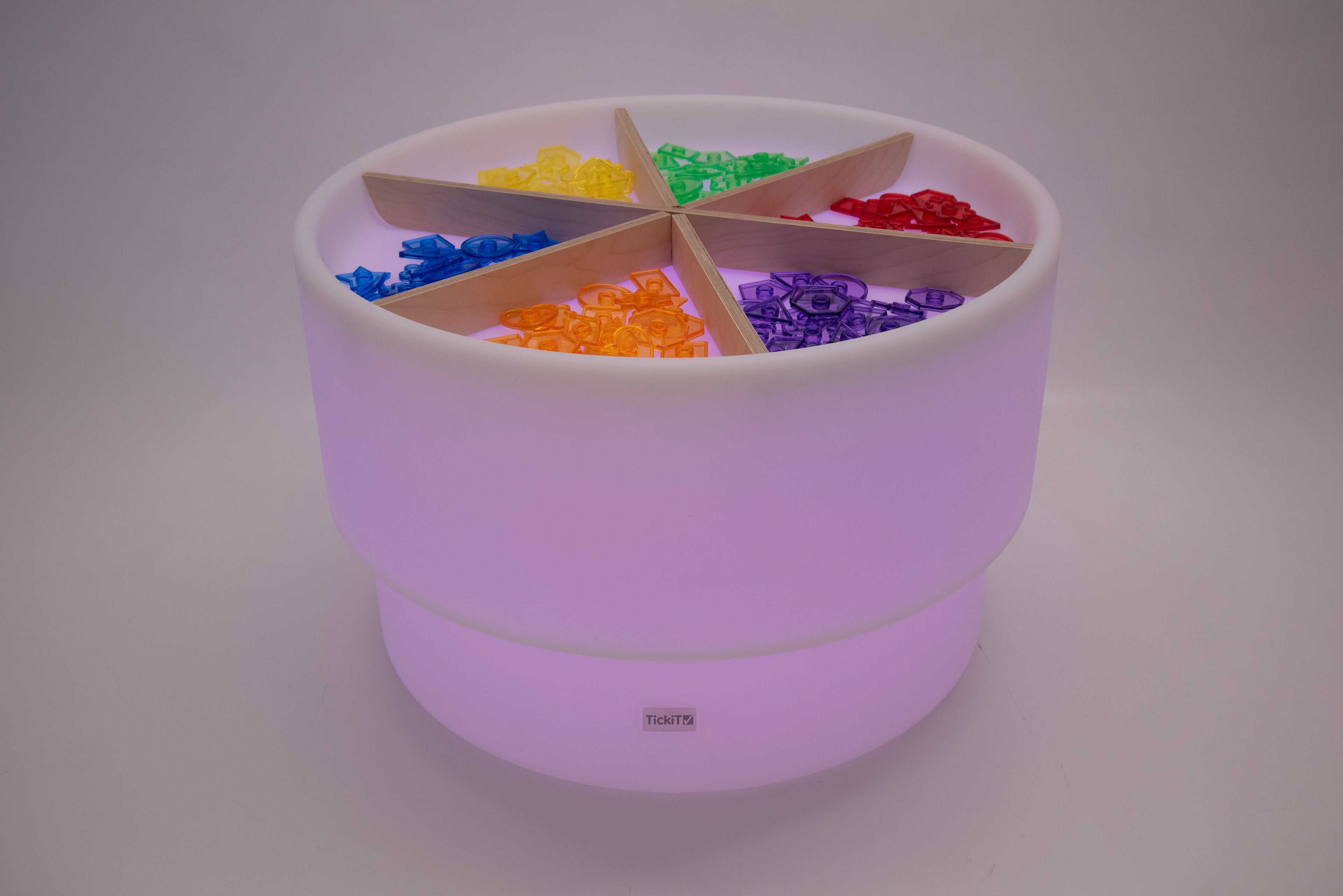 Light wood divider cross inside lilac round storage bin with multicolor blocks
