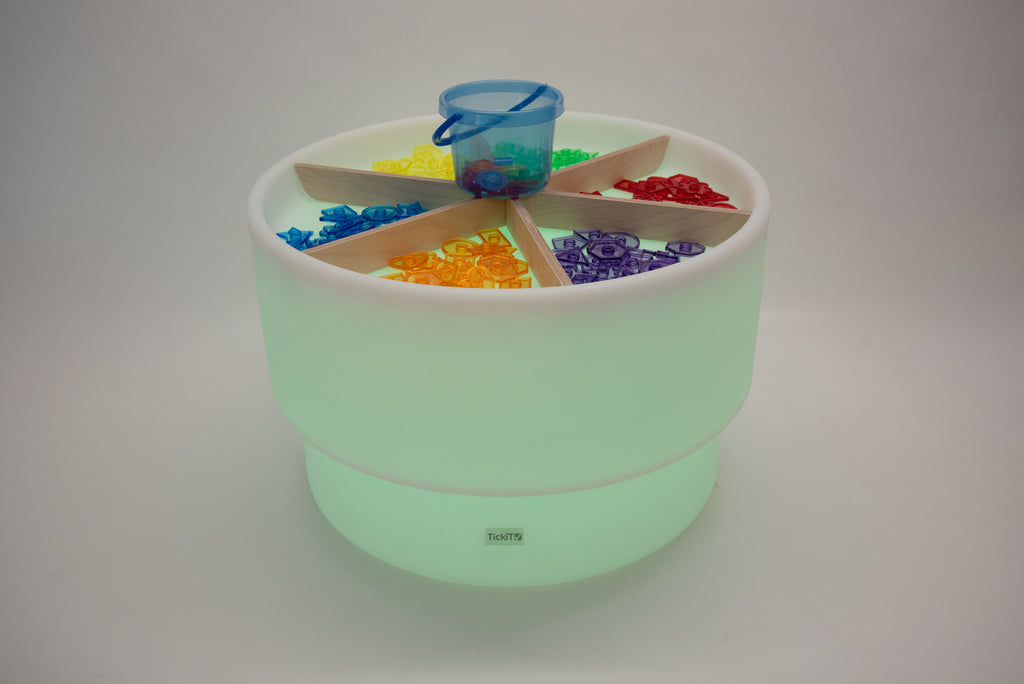 Light wood divider cross inside mint green round storage bin with colorful blocks