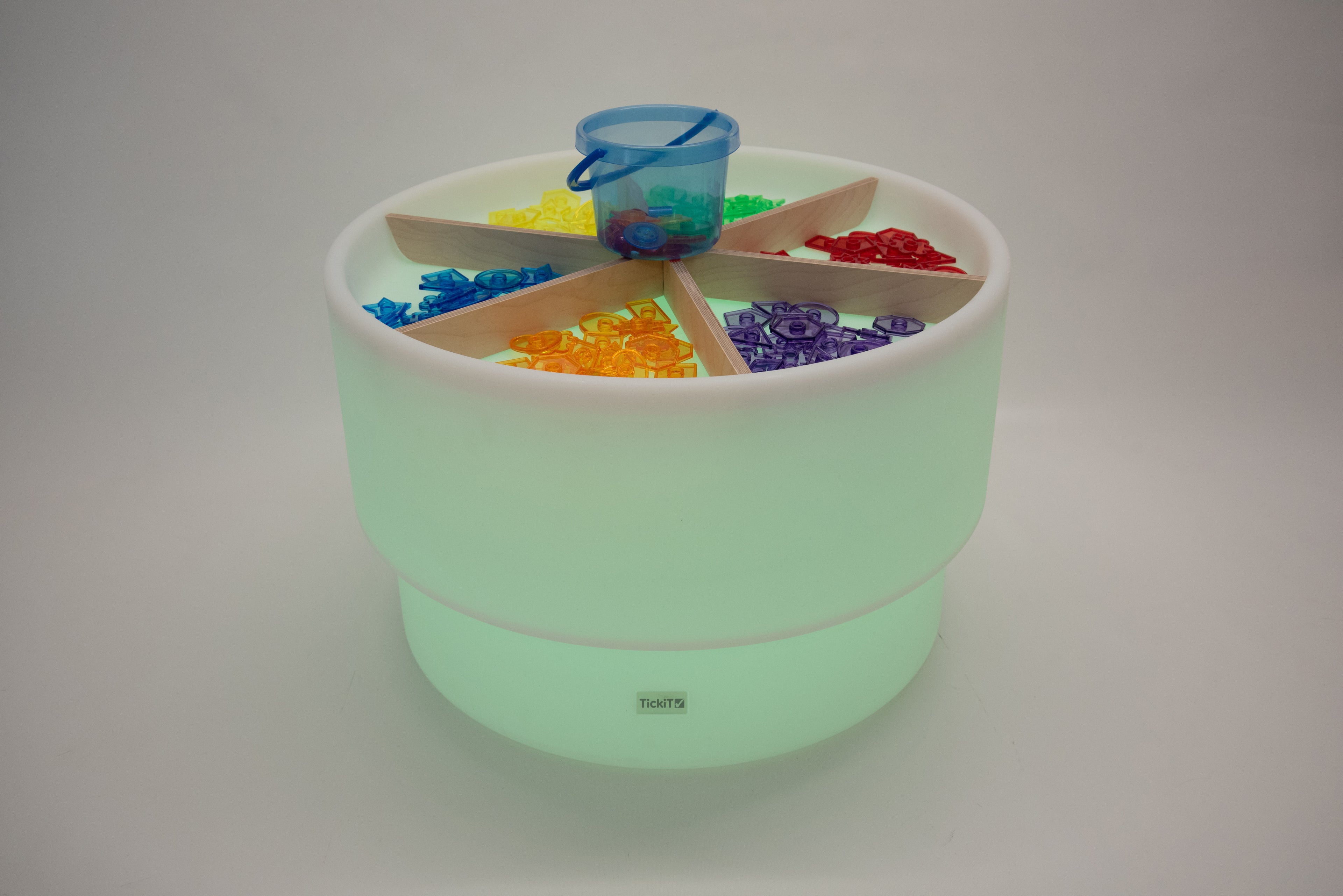 Light wood divider cross inside mint green round storage bin with colorful blocks