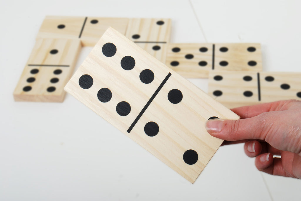 Wooden domino tiles with black dot pips in a hand, stacked and ready to play