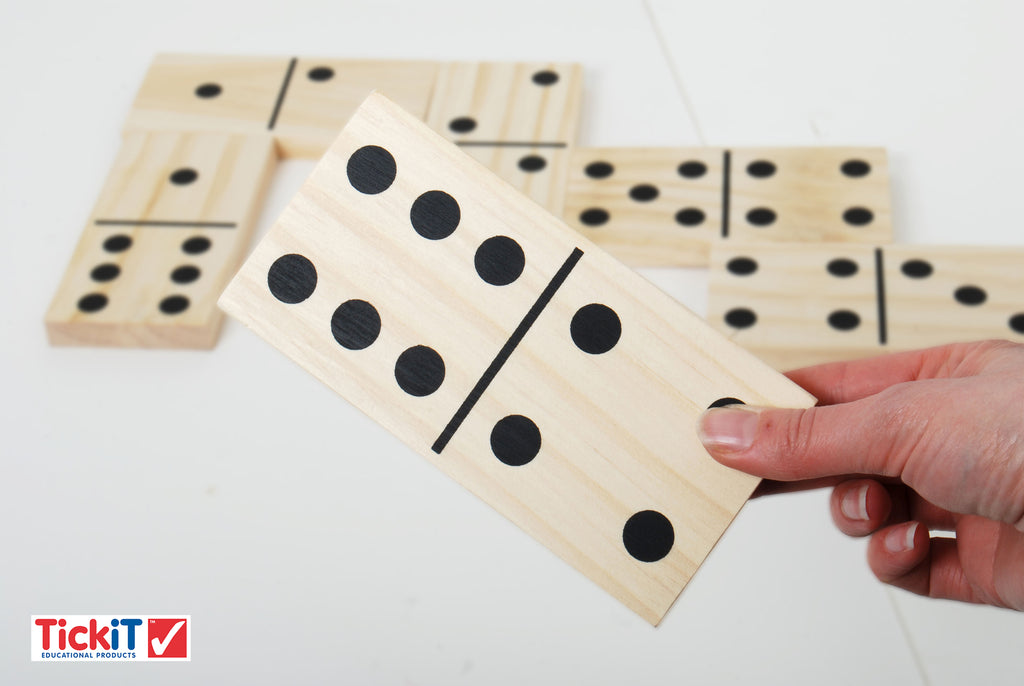 Hand holding wooden domino tiles with black dot pips, close-up view