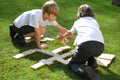 Children playing with wooden domino tiles with black dot pips on the floor