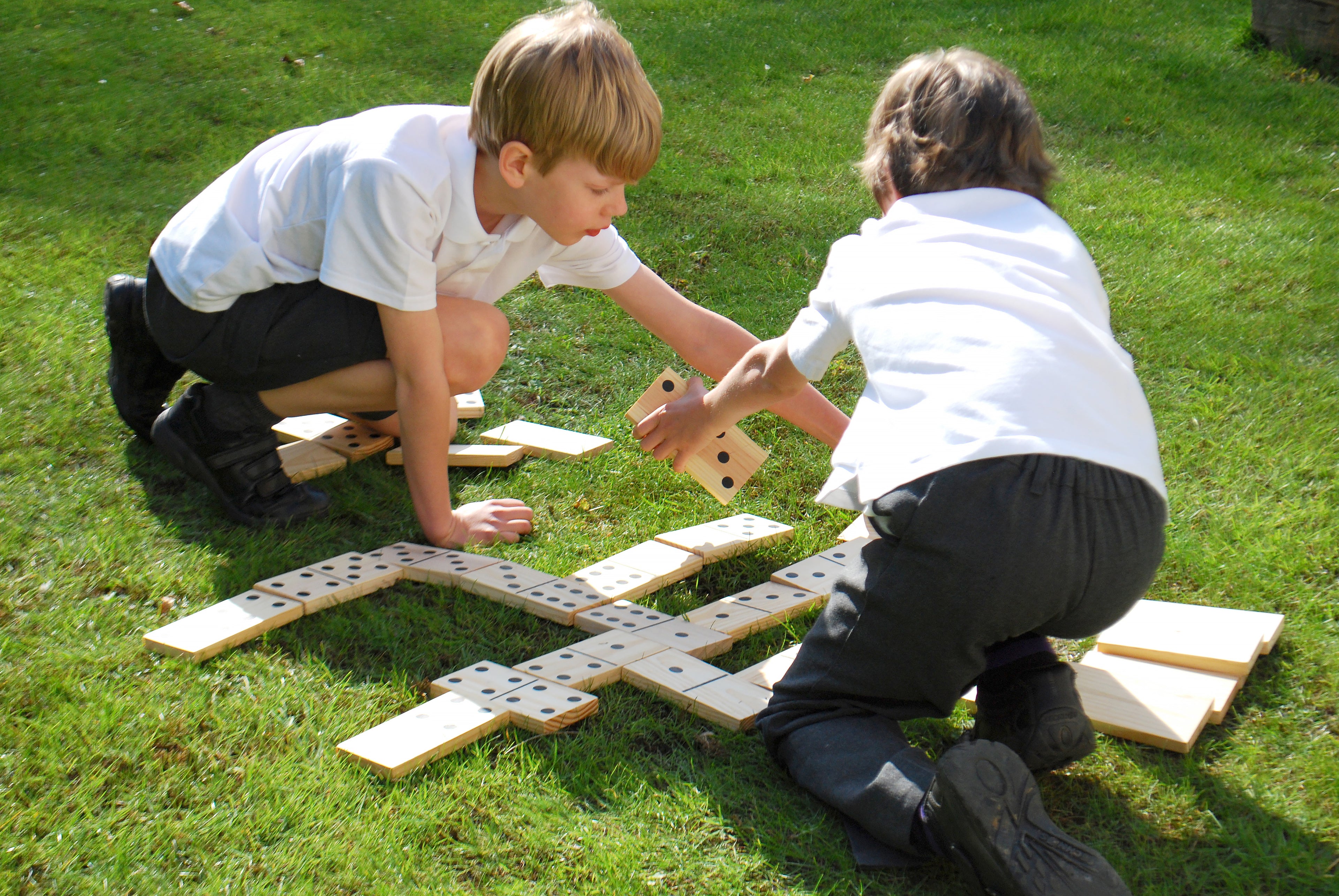 Children playing with wooden domino tiles with black dot pips on the floor