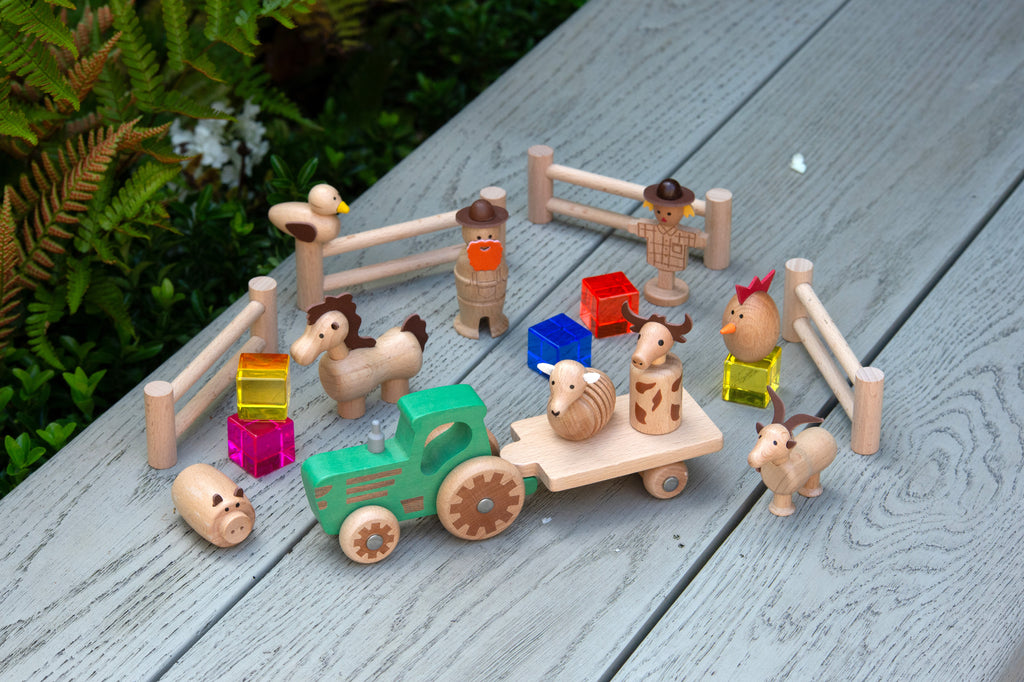 Wooden farm toy set close-up with tractor, barn, fence and animal figures
