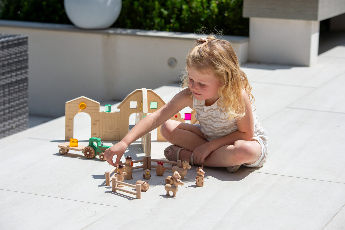 Wooden farm toy set with tractor and animal figures while child plays