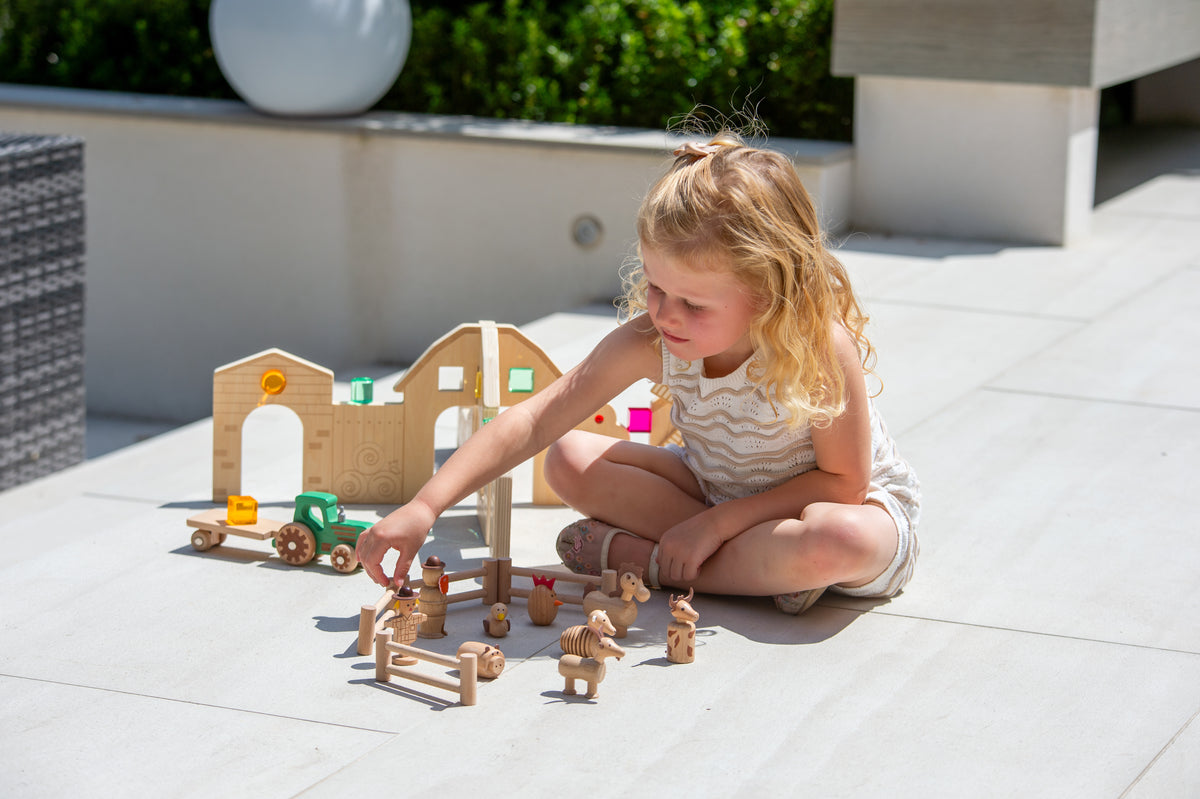 Wooden farm play set with barn, fence pen and animal figures on patio