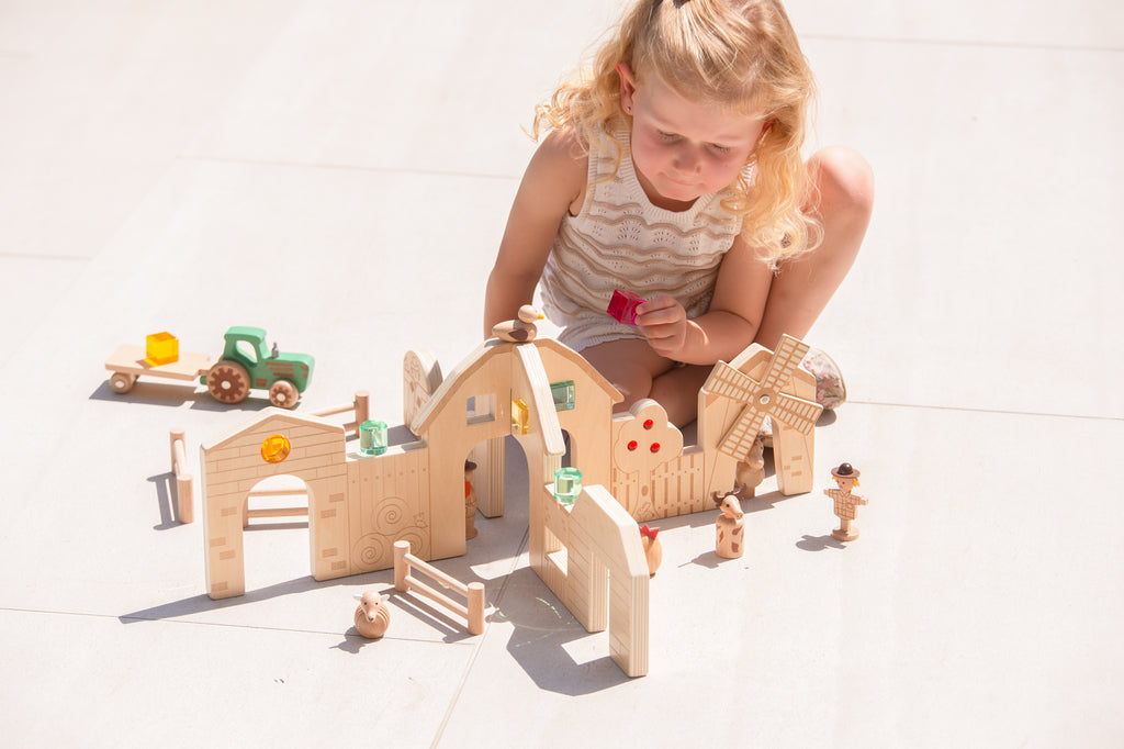 Wooden farm toy set on floor with barn, fence pen and animal figures