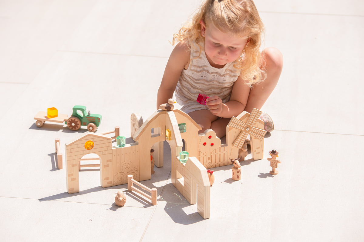 Wooden farm toy set on floor with barn, fence pen and animal figures