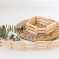 Light wood picket fence sections with small curved gate, arranged in a ring