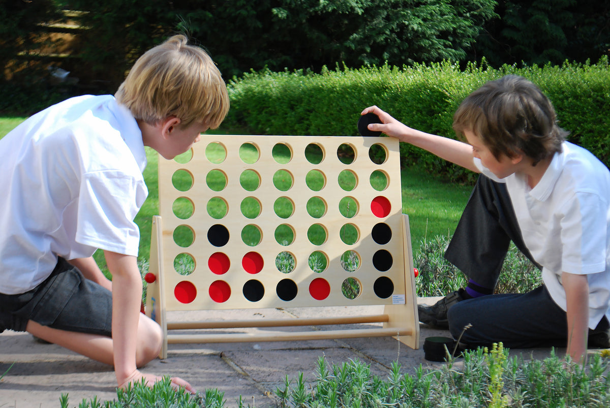Wooden Connect Four board with green disc pattern and scattered round pieces