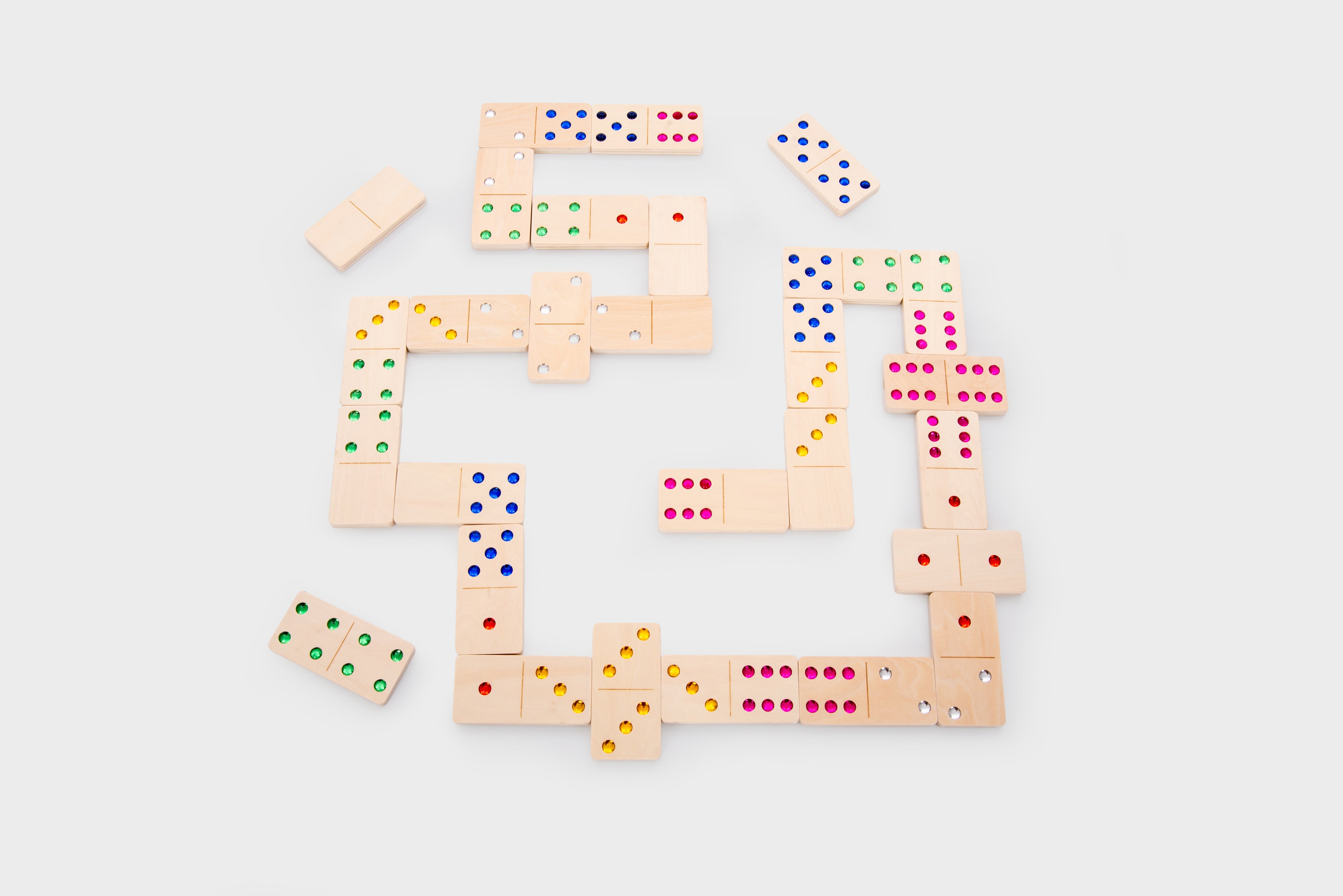 Wooden dominoes in an oval pattern with multicolored dot pips, top view.