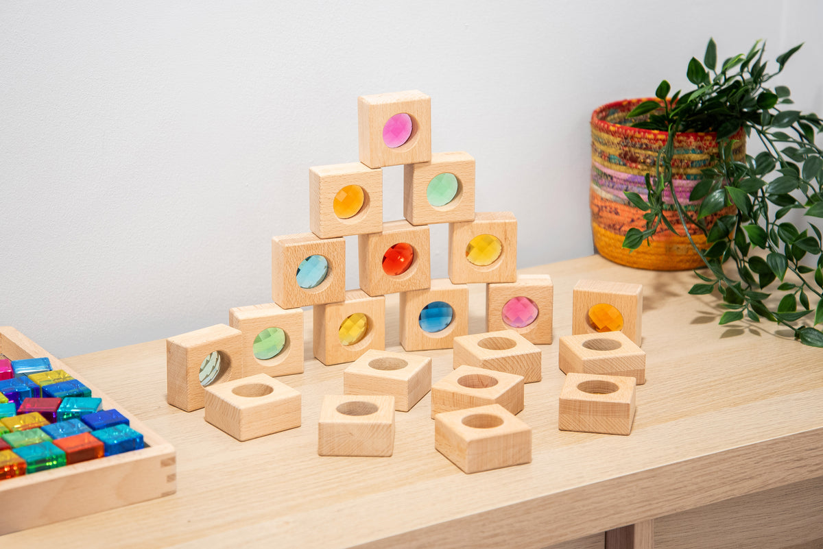 Wooden kaleidoscope blocks with square cubes and colored circular inserts on a light wood table