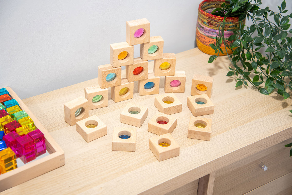 Wooden kaleidoscope blocks scattered on a tabletop, featuring square cubes with colorful circular inserts