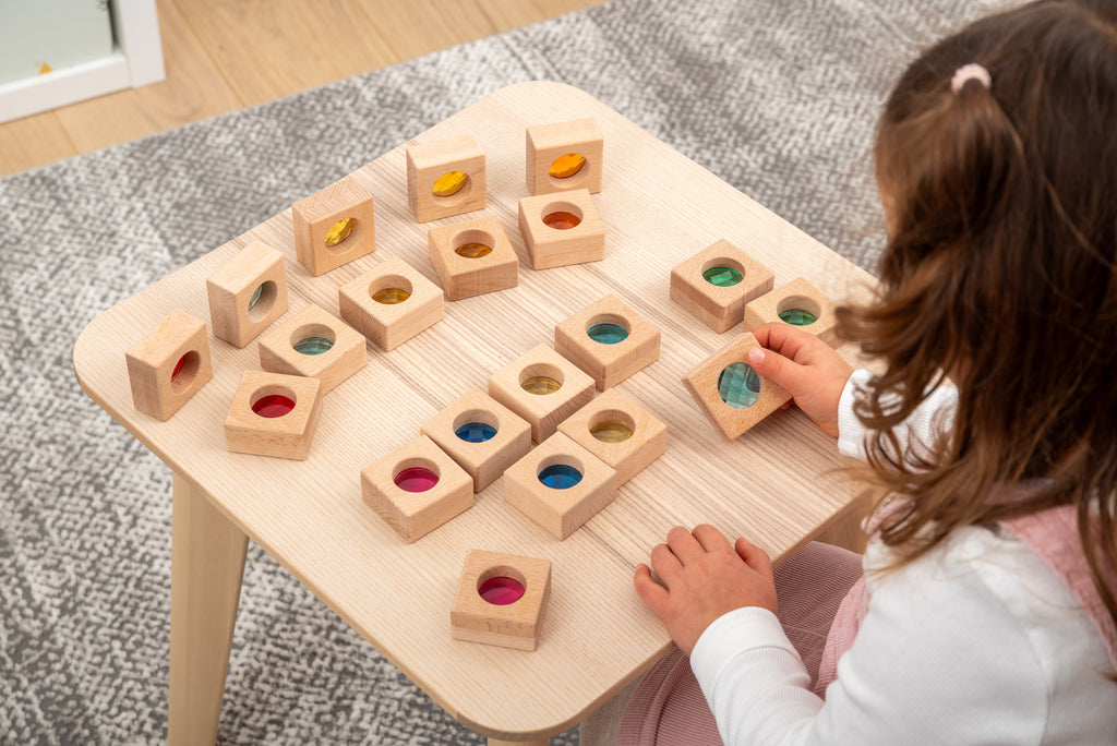 Child playing with wooden kaleidoscope blocks; square pieces with colored circular insets
